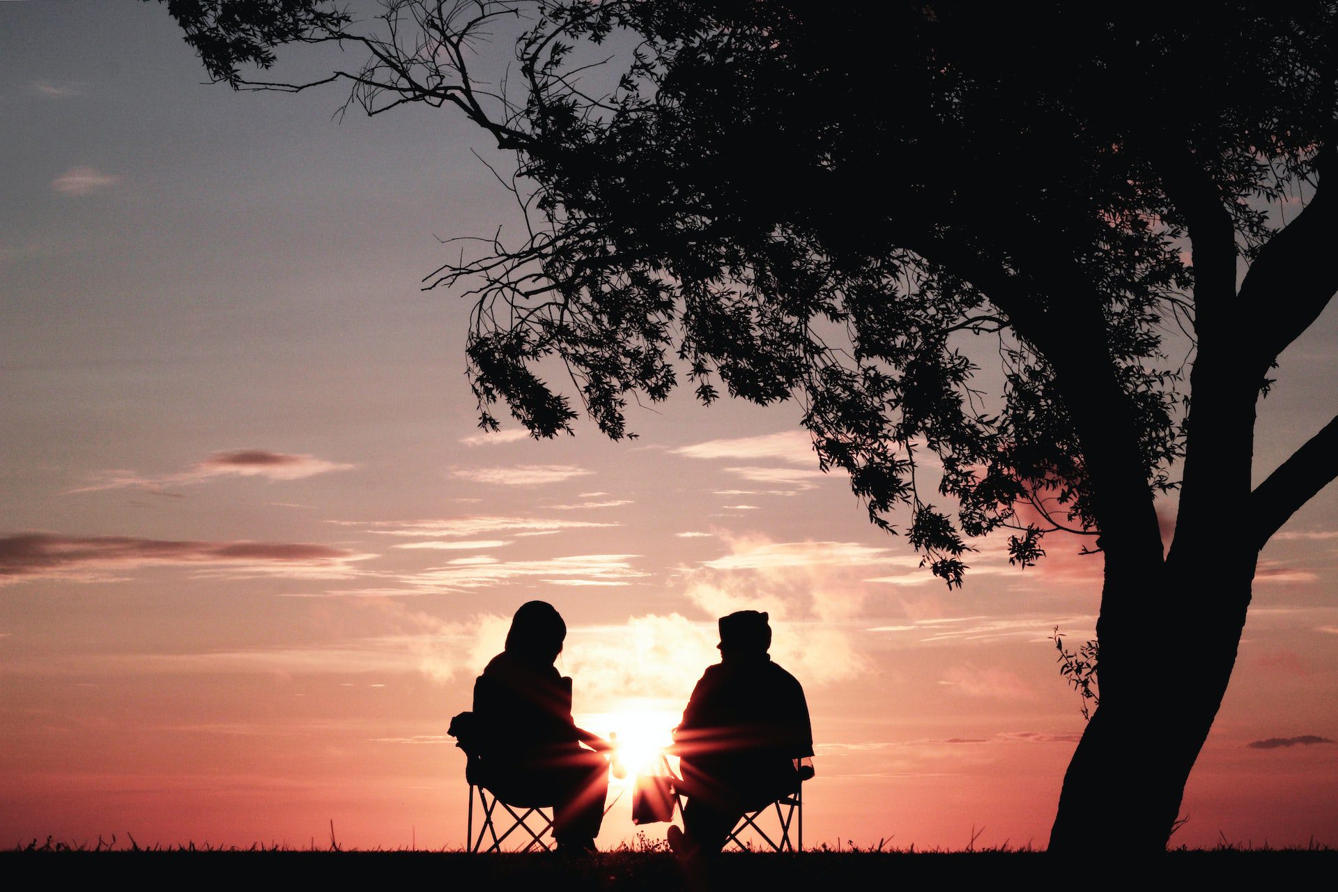 Two people sitting outside at sunset